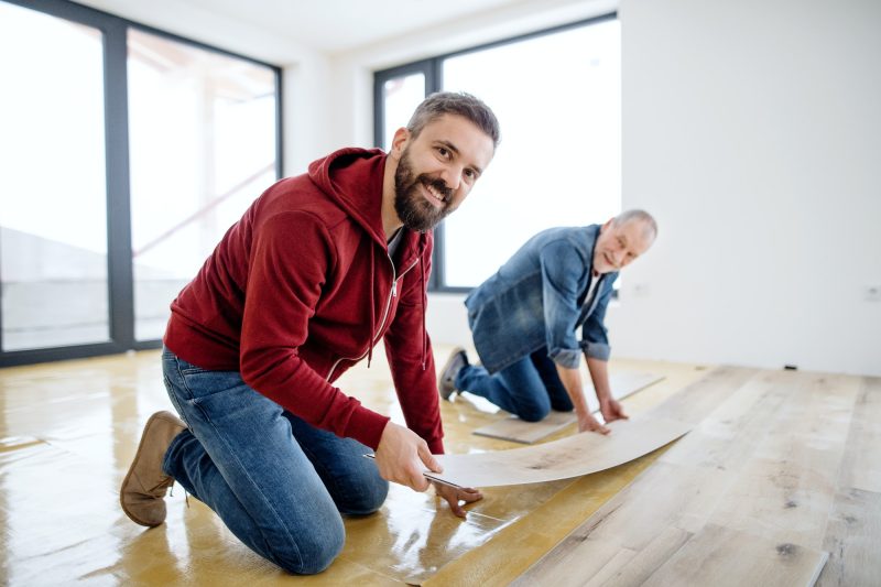 a-mature-man-with-his-senior-father-laying-vinyl-flooring-a-new-home-concept-.jpg a-mature-man-with-his-senior-father-laying-vinyl-flooring-a-new-home-concept-.jpg